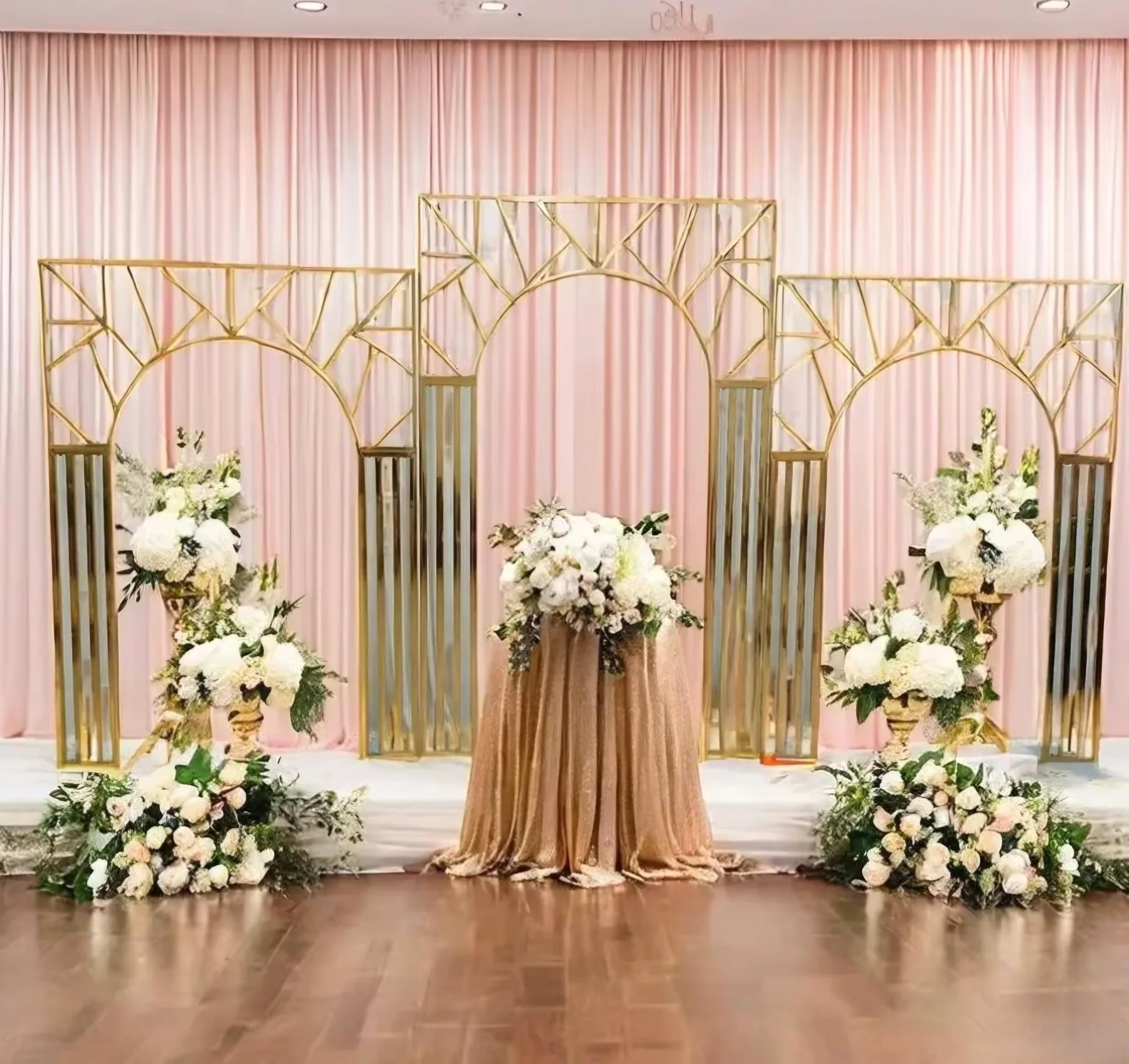 Blush and gold event stage with floral stands and decorative backdrop panels