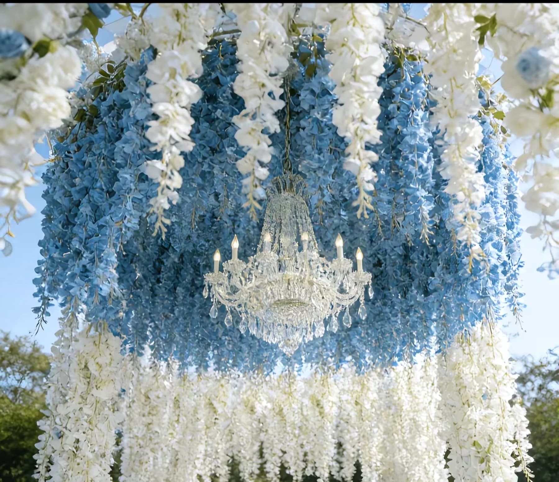 White hanging floral canopy with chandelier over an event setup